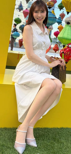 Woman in a white dress sitting outdoors with colorful lanterns in the background