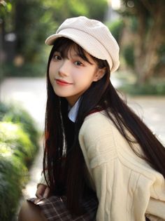 Young woman with long dark hair wearing a hat and sweater outdoors