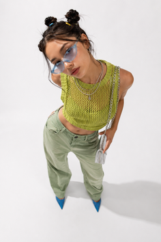 Woman with space buns and blue sunglasses wearing a green knit top and pants