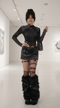 Woman in a dark outfit with a denim skirt and furry leg warmers indoors
