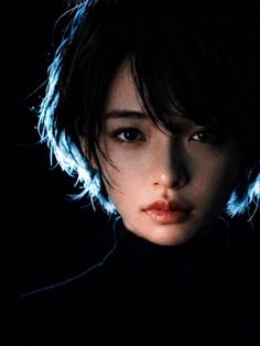 Woman with short black hair in a turtleneck with dramatic blue backlight