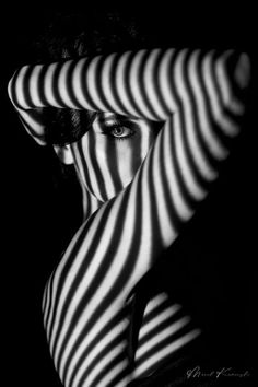 Black and white portrait with striped shadows across the subject's face and arms