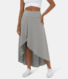 Woman in a gray high-low skirt and white crop top with white sneakers