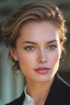 Woman with blue eyes and blonde hair in an updo wearing a black blazer