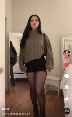 Woman in a turtleneck sweater, mini skirt, and tights posing indoors