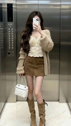 Woman in a lace top, mini skirt, and boots taking a mirror selfie in an elevator