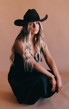 Woman with long blonde hair and a cowboy hat in a black dress