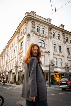 Woman with red hair in a grey blazer on a city street