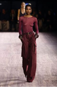 Model in a sheer top and cargo pants on a dark runway