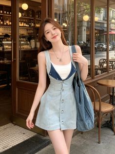 Woman in a denim dress and white top standing outside a cafe