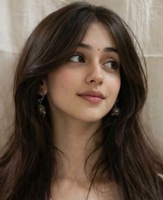 Woman with long dark hair and earrings looking to the side