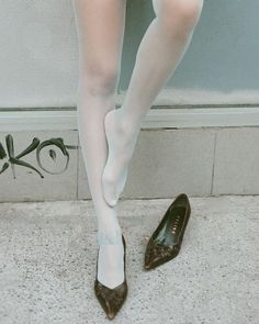 Person wearing white tights and brown high heels with one shoe off