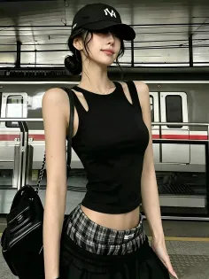 Woman in a black crop top and plaid skirt at a train station