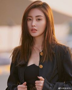 Woman with long brown hair wearing a black jacket and top