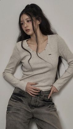 Woman with long dark hair in a ponytail wearing a long sleeve shirt and jeans