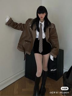 Woman in a brown aviator jacket, white shirt, and black shorts with a striped tie