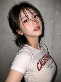 Woman with dark hair in a messy bun wearing a tight white t-shirt