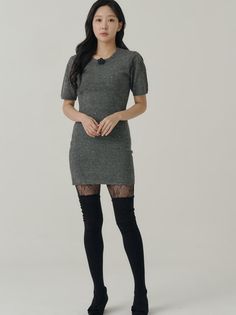 Woman in a gray dress with fishnet stockings and thigh-high socks in a studio