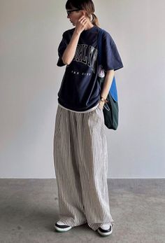 Person in an oversized t-shirt and striped pants with a ponytail and glasses