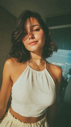 Woman with short hair and freckles wearing a halter top and layered necklaces