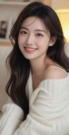Smiling woman with long dark hair wearing a white off-shoulder sweater
