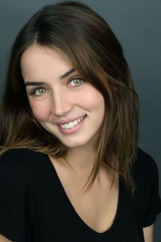 Woman with green eyes and brown hair smiling in a black shirt