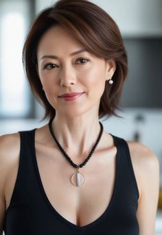 Woman with short hair wearing a black tank top and beaded necklace