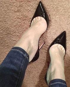 Person wearing black pointed-toe high heels and jeans on a brown carpet