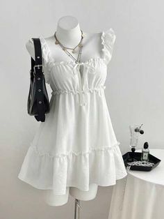 White ruffle strap dress on a mannequin with a black handbag and layered necklaces
