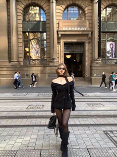 Woman in a black off-shoulder top and fishnet stockings on a city street