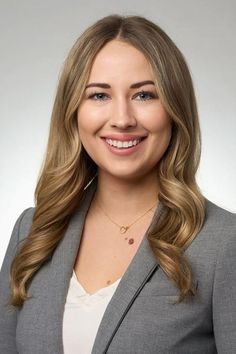 Blonde woman in a gray suit and white top smiling in a studio portrait