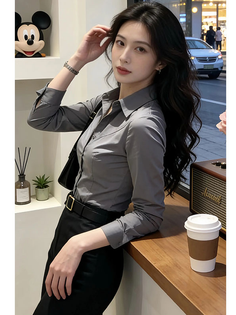 Woman in a gray shirt and black pants leaning on a counter indoors