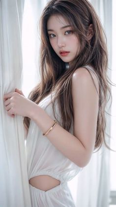 Woman with long brown hair in a white dress with cutouts and a gold bracelet