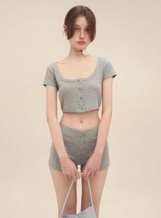 Woman in a gray crop top and shorts with a white choker
