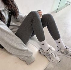 Person wearing gray ribbed leggings, white socks, and sneakers indoors