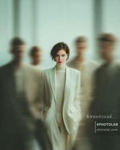 Woman in a white suit with blurred figures in the background