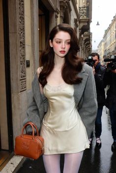 Woman in a slip dress and fur coat on a street with paparazzi