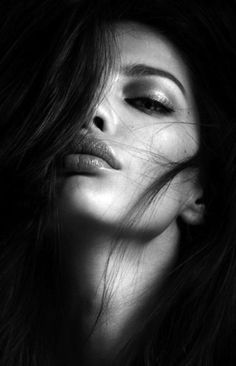 Black and white close-up portrait of a woman with long hair covering part of her face