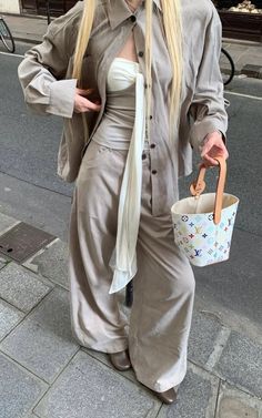 Woman with long blonde hair wearing an oversized shirt and wide-leg pants on a street
