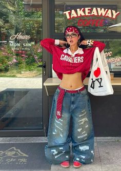Woman in a red crop top, baggy jeans, and bandana posing outdoors