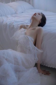 Woman in a white ruffled dress with bare shoulders in a bedroom
