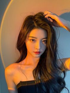 Woman with long black hair in a strapless top with warm dramatic lighting