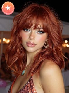Woman with red wavy hair and bangs wearing a sequin top and jewelry