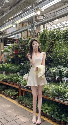 Woman in a white top and pleated skirt with a face mask in a plant nursery
