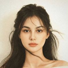 Woman with long dark hair and exposed shoulders against a light background