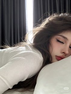 Woman with long hair and closed eyes lying on a pillow with backlight
