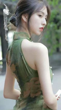 Woman in a green cheongsam with a decorative hair ornament looking over her shoulder
