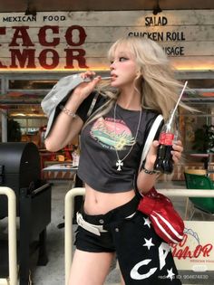 Blonde woman in a crop top and shorts holding a drink outdoors