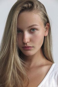Close-up portrait of a young woman with long blonde hair and green eyes