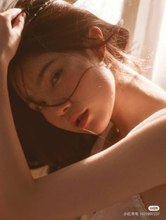 Woman with brown hair in soft, warm lighting with exposed skin